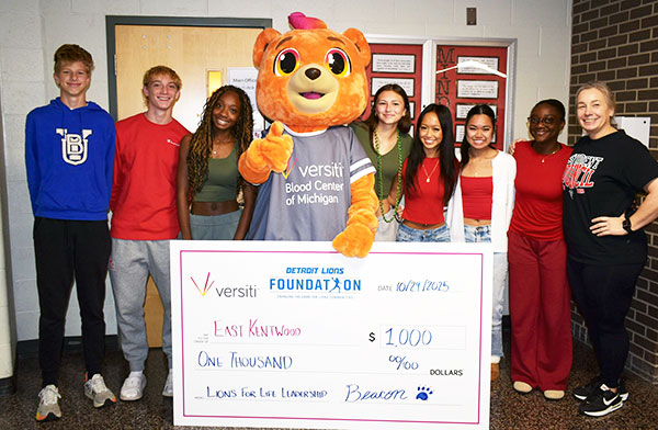 Beacon the Bear holding a $1,000 check donated by the Detroit Lions Foundation.